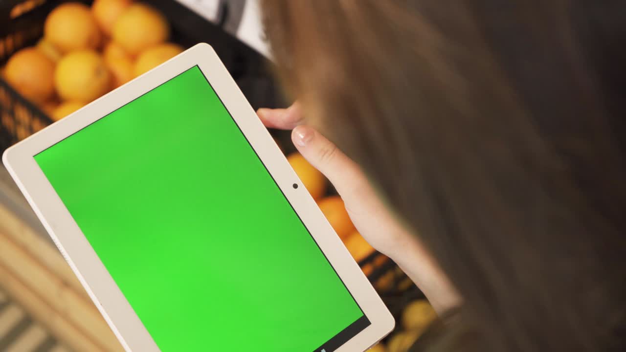 primer plano de la mano de una mujer joven sosteniendo una tableta con un diseño de pantalla verde. vista superior