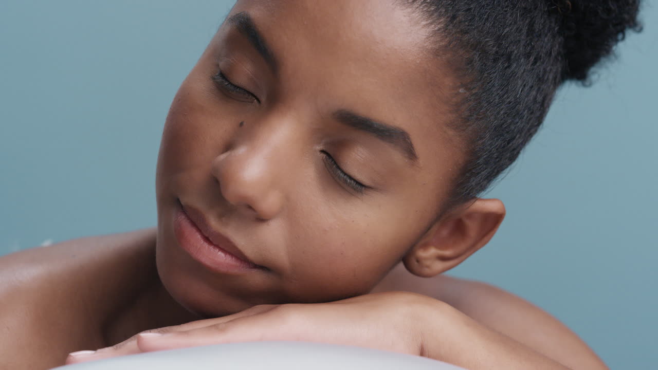 close up portrait beautiful young african american woman relaxing feathers falling on soft natural skin gently caressing healthy complexion in slow motion skincare concept