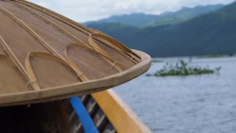 traditional myanmar bamboo hat on person boating across inle lake