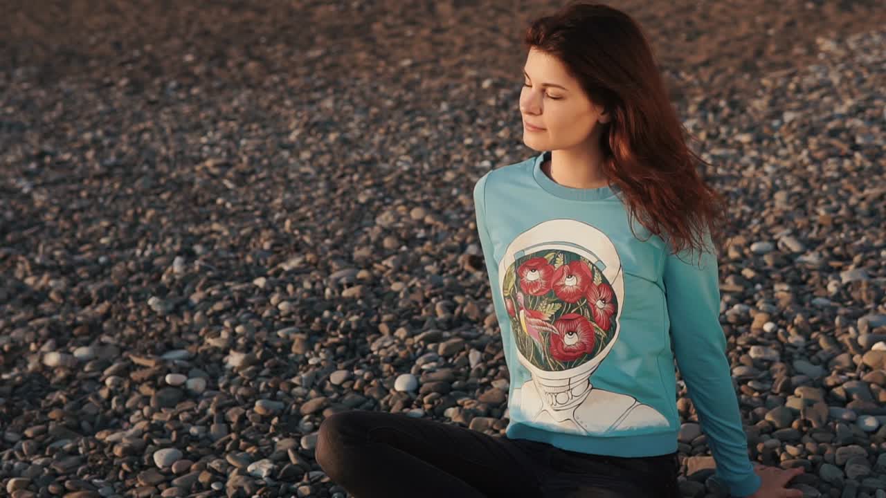 mujer meditando en una playa de guijarros al atardecer