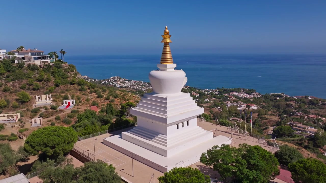 Riprese con drone di Benalmadena, Andalusia, Spagna, che sorvolano una stupa bianca su una collina con mare blu calmo, cieli sereni e viste panoramiche della costa.