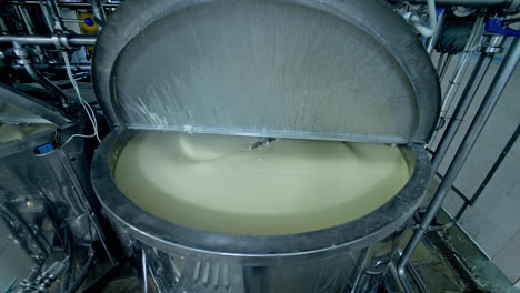two big steel tanks full of cream with automatic mixing. metal reservoirs with open lids at the modern milk factory. close up.