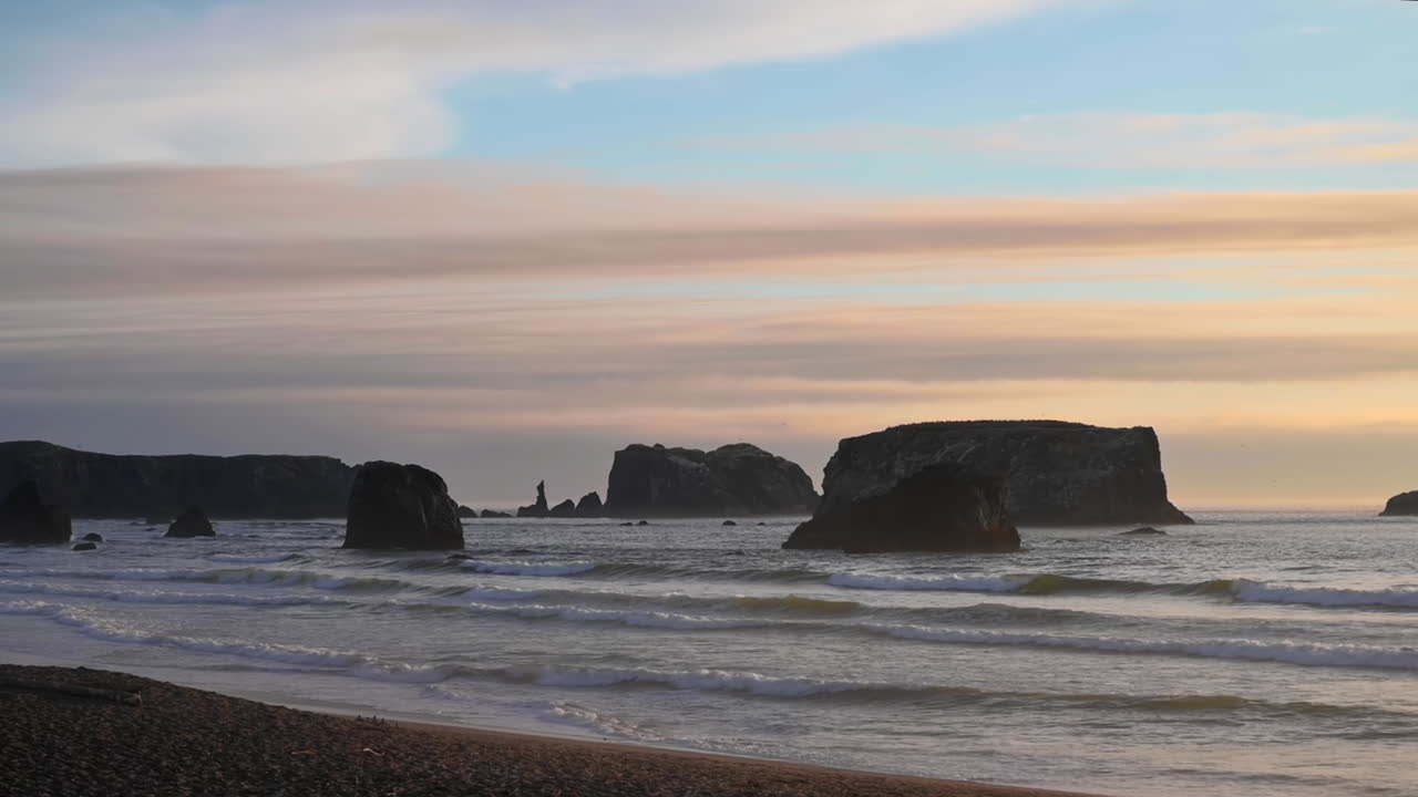 playa vacía en bandon, oregon con vistas a las pilas de mar contra el colorido cielo de la puesta de sol - toma amplia, estática