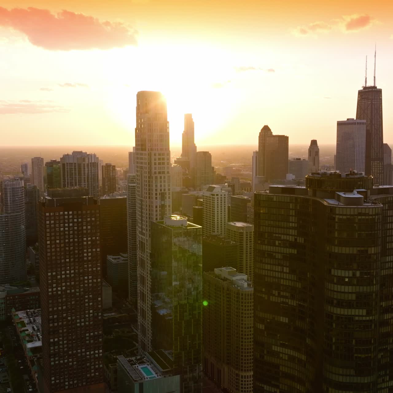 Sol brilhante se pondo atrás dos deslumbrantes arranha-céus de Chicago. Estradas de várias faixas com diversos carros andando à beira-mar. Vista superior