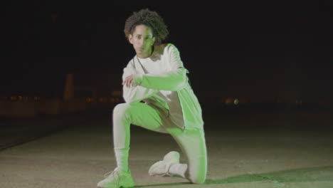 stylish young guy dancing at night outdoors