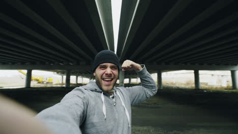 man taking a selfie under a highway overpass