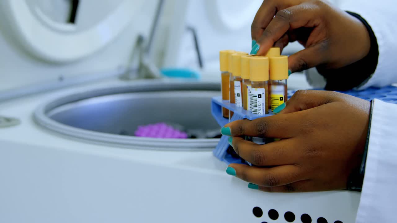 Laboratory technician taking out blood plasma samples from centrifuge 4k