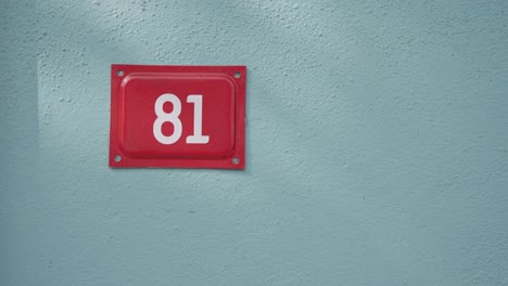 red house number 81 sign on a blue wall
