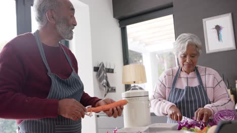 Senior-biracial-couple-peeling-and-chopping-vegetables-in-kitchen,-unaltered,-in-slow-motion