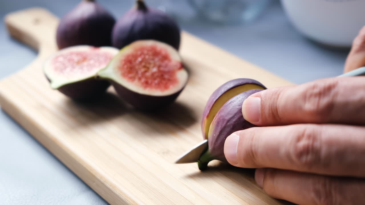 Manos del chef cortando higos en una tabla de cortar