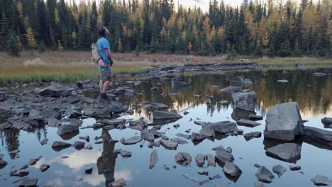 caminante en las rocas del estanque mirando alrededor de kananaskis, alberta, canadá