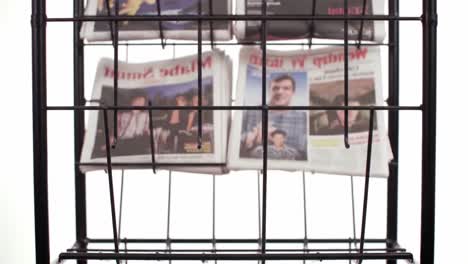 a display of newspapers organized in a rack showcasing various headlines and themes, representing diverse news coverage and print media presentation