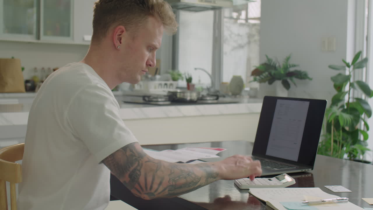 Young Man Paying Bills Online with Laptop at Home