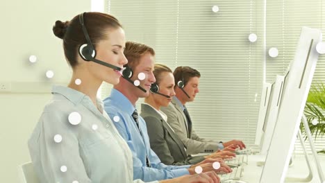 Animation-of-white-dots-over-business-people-wearing-phone-headsets