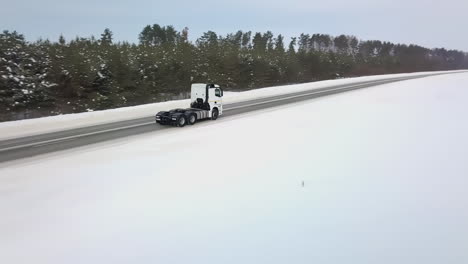 white semi-truck driving on snowy road