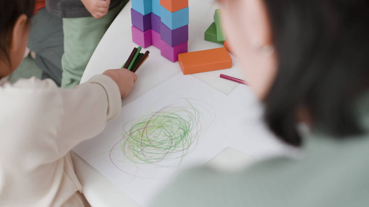 Child Drawing with Crayons and Building Blocks
