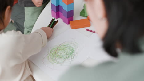 child drawing with crayons and building blocks