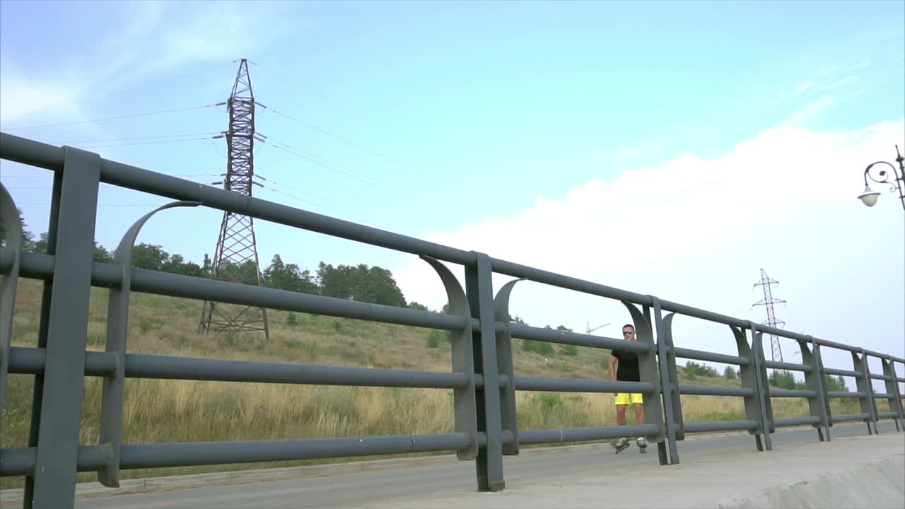 hombre patinando en una calle de la ciudad junto a una valla.