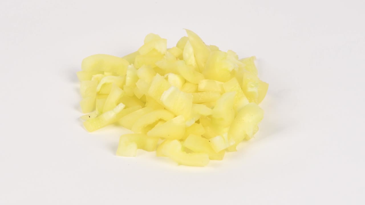 pimienta amarilla en cubitos. concepto de alimentos saludables. preparación de verduras para ensalada. movimiento de bucle. vista lateral. rotación 360.