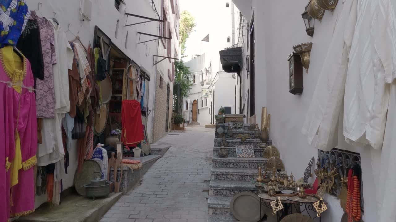 Static shot of tranquil narrow street with Clothes hanging outside a shop, Tangier, Morocco