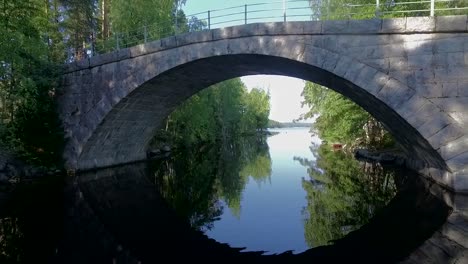 drone flying under an old stone bridge