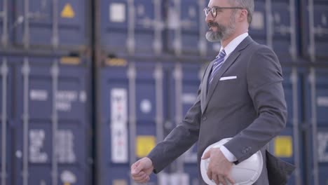ejecutivo de mediana edad, gerente o inversor caminando sonrisa y saludo de apretón de manos con el ingeniero masculino profesional en el patio de carga de contenedores. socios de negocios apretones de manos para trabajar o acordar la inversión juntos.
