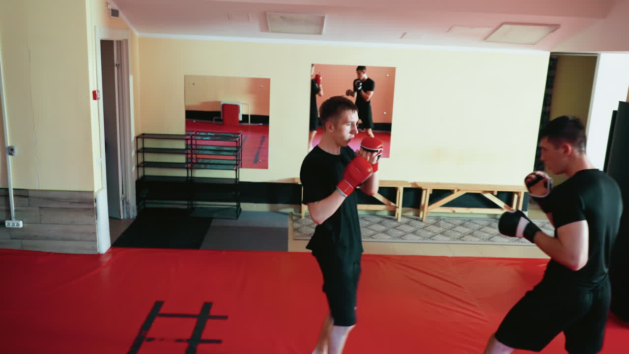 Karate practitioners preparing for sparring session inside martial arts gym, focused fighters on red mat in guard stance, demonstrating concentration, discipline, combat skills, training, mental strength