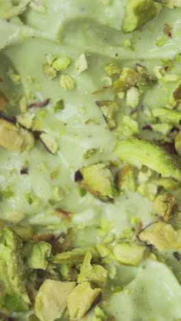 vertical macro shot of pistachio ice cream with raw nuts on top