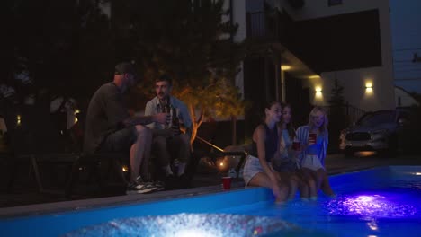 a group of friends chatting and spending time near the pool in a country house during their vacation in the evening