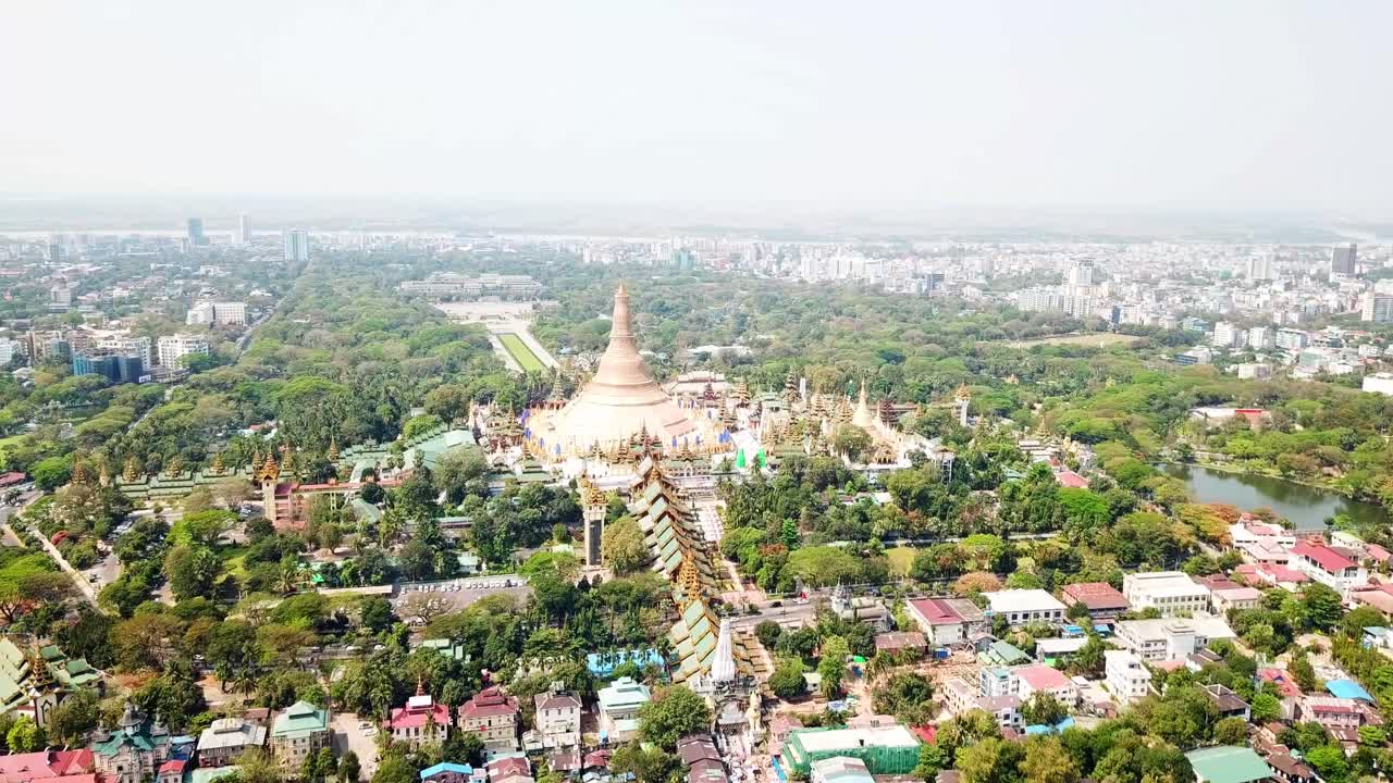 Aerial view captures the sprawling landscape of Rangun, Myanmar, showcasing the numerous buddhist temples and pagodas interspersed with lush greenery and the cityscape in the background