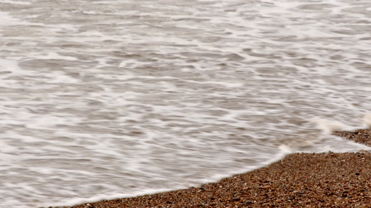 추운 겨울의 파도가 ingoldm musicells, skegness 모래 해변에 부 ⁇ 히고 있습니다.