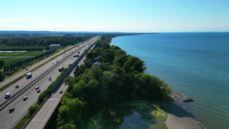 aerial parallel to busy qew highway over lake ontario shore - lincoln, ontario