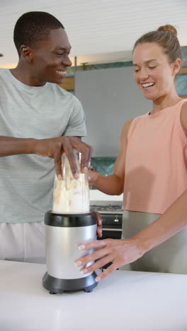 vertical video: blending smoothie, smiling couple enjoying time together in kitchen