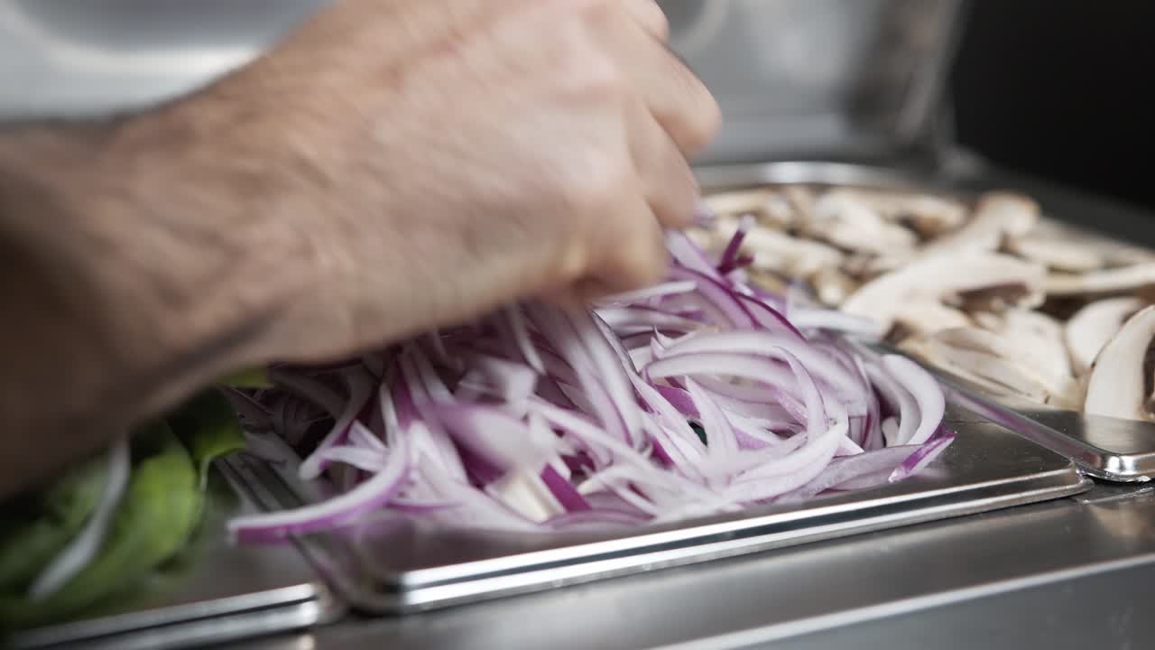 la mano de un chef experto toma un puñado de cebollas de la bandeja de metal