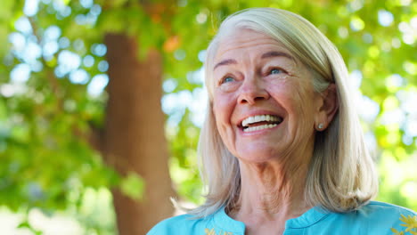 portrait of smiling senior woman standing outdoors in garden park or countryside