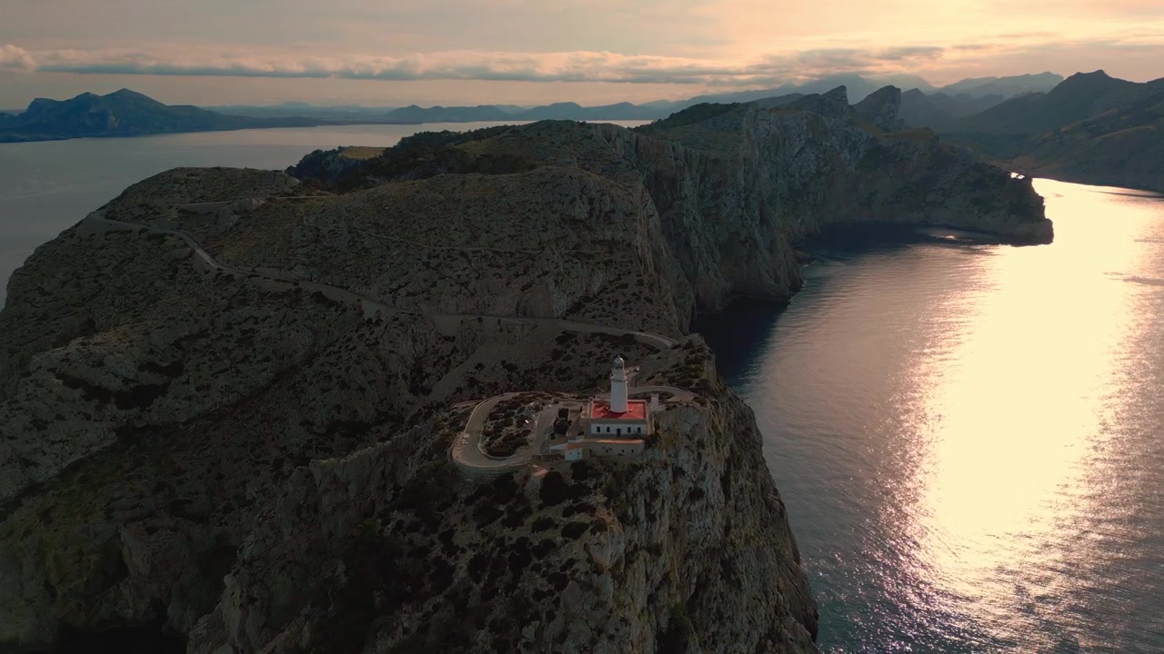 Faro iconico di Cap de Formentor con scogliere drammatiche, montagne e formazioni rocciose al tramonto. Bellezza naturale del mare blu profondo sull'isola balearica di Palma di Maiorca. Spettacolare ripresa aerea con drone in 4K UHD.
