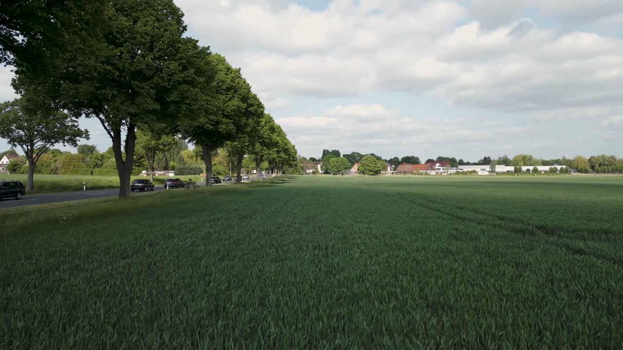 drone aéreo disparo de coches que se mueven rápidamente a lo largo de la autopista, rodeados de granjas verdes en brunswick, alemania en un día nublado
