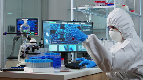 Doctor-in-ppe-suit-looking-at-blood-sample-in-test-tube