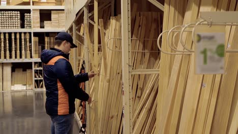 un joven elige vigas de madera en una tienda de materiales de construcción