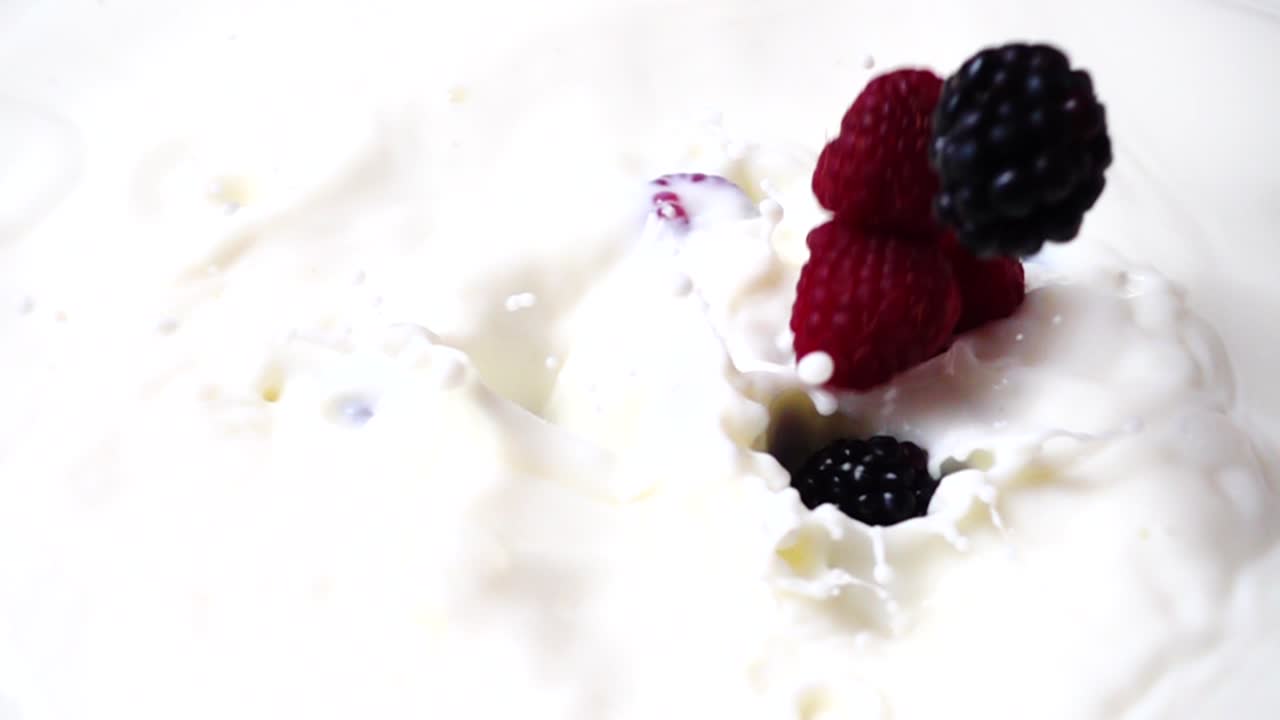 Falling of raspberry and blackberry in milk. Slow motion. Shooting of fruit. Slow motion