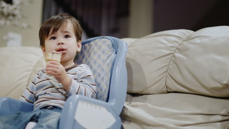 two years old asian baby eats ice cream, sits in a child seat for feeding