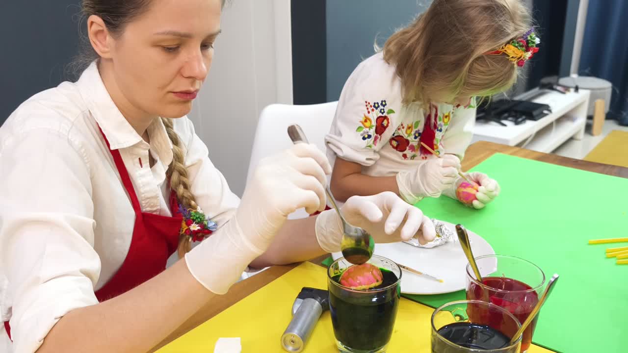 мать и дочь вместе украшают пасхальные яйца.