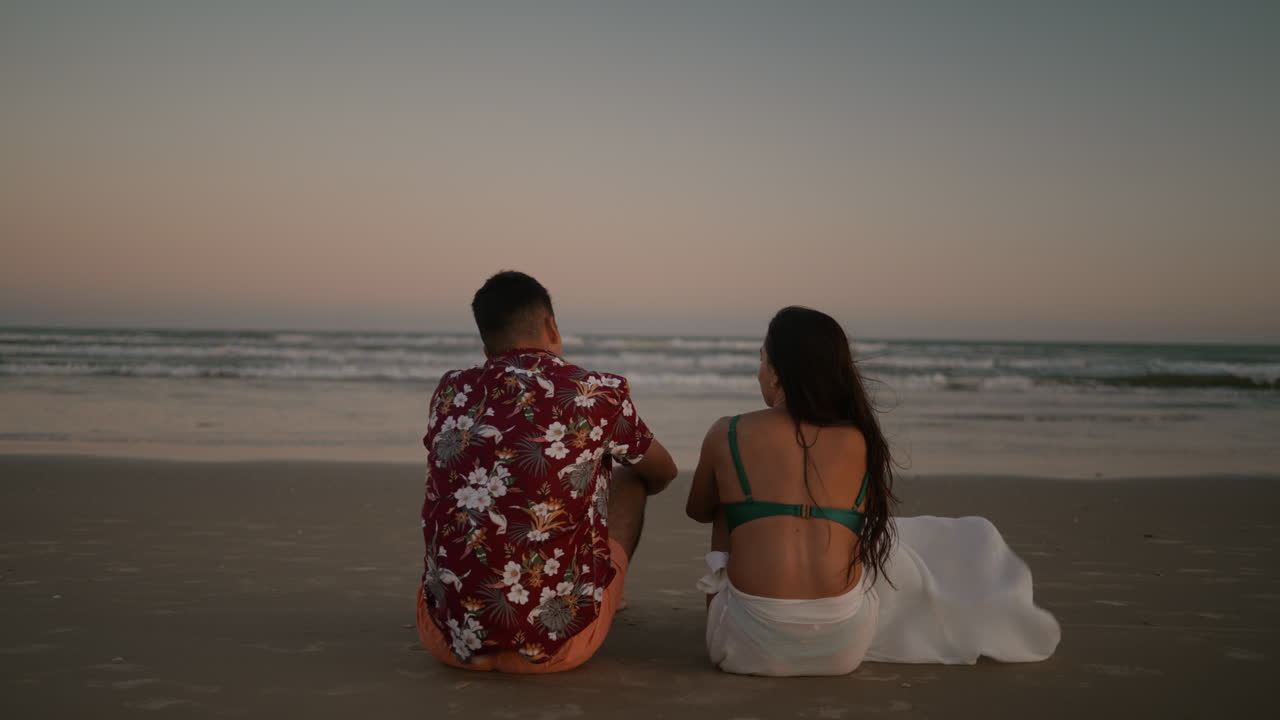 una pareja feliz sentada en la arena.
