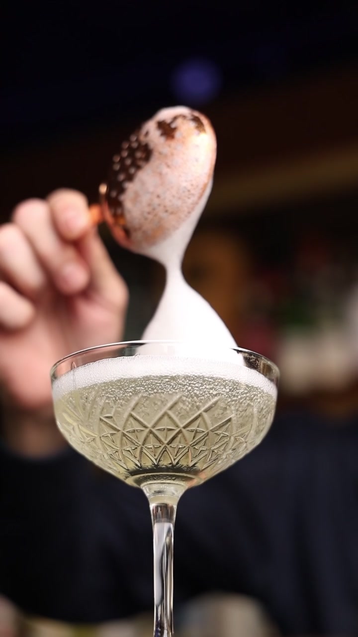 Barman che aggiunge schiuma a un bicchiere da cocktail di cristallo