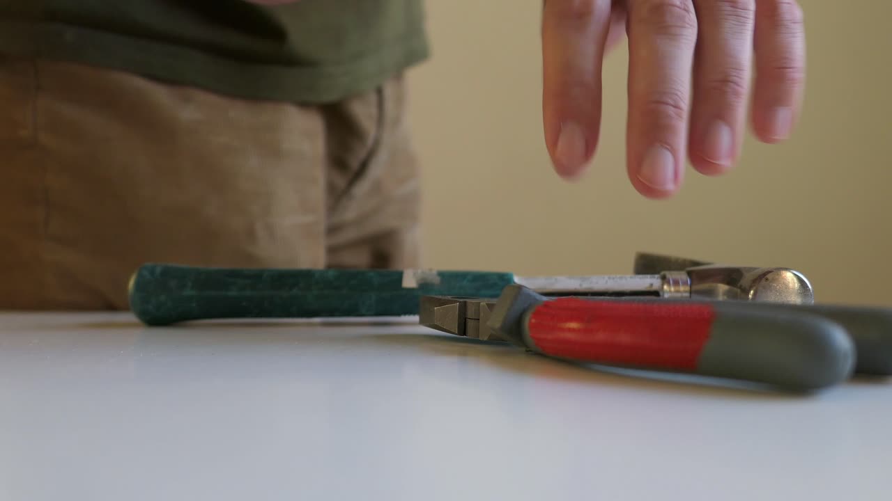 hombre agarrando destornillador, pinzas y herramientas de martillo, de cerca