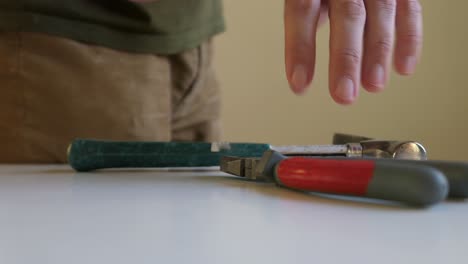 man grabbing screwdriver, pliers and hammer tools, close up