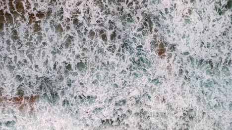 aerial view of a wave breaking on a golden sandy beach, the mesmerizing patterns of foam and surf