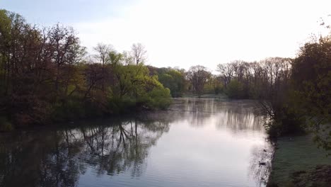 small lake covered with fog between trees in the morning