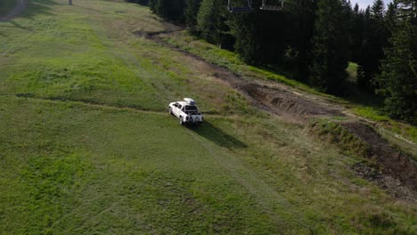 slow aerial panning shot of white pick up truck climbing uphill during the day