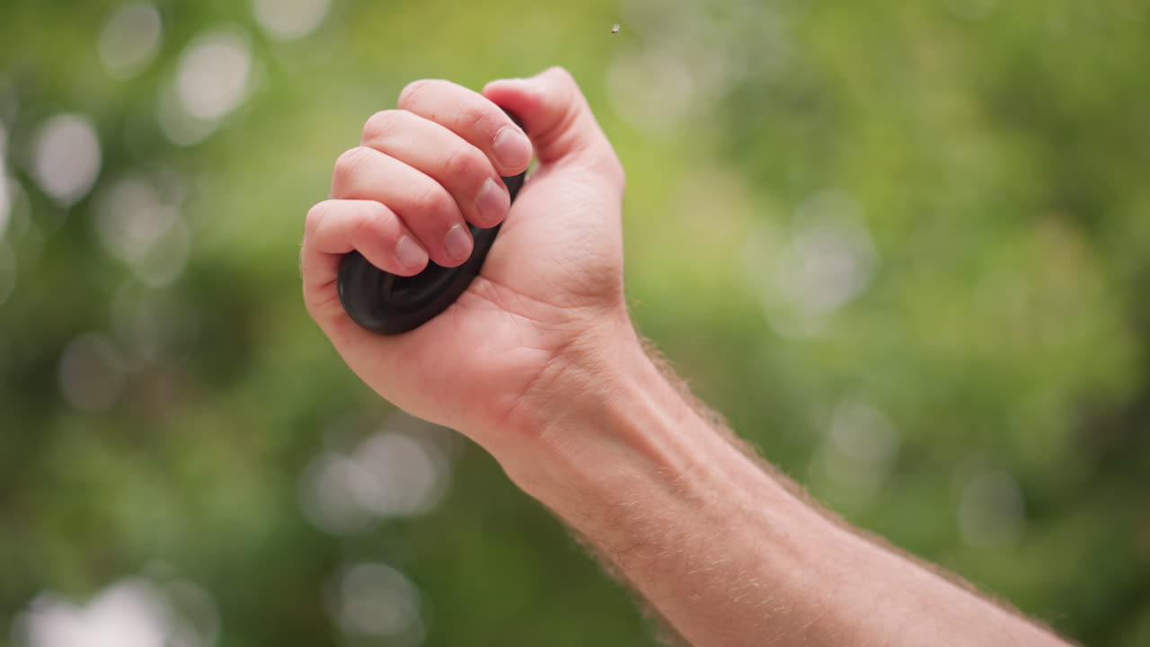 Closeup Of Man Practicing Stress Relief Outdoors, Man Engaging In Calming Hand Exercise In Park Setting, Individual Performing Hand Squeezing Exercise Outdoors To Reduce Stress And Increase Focus